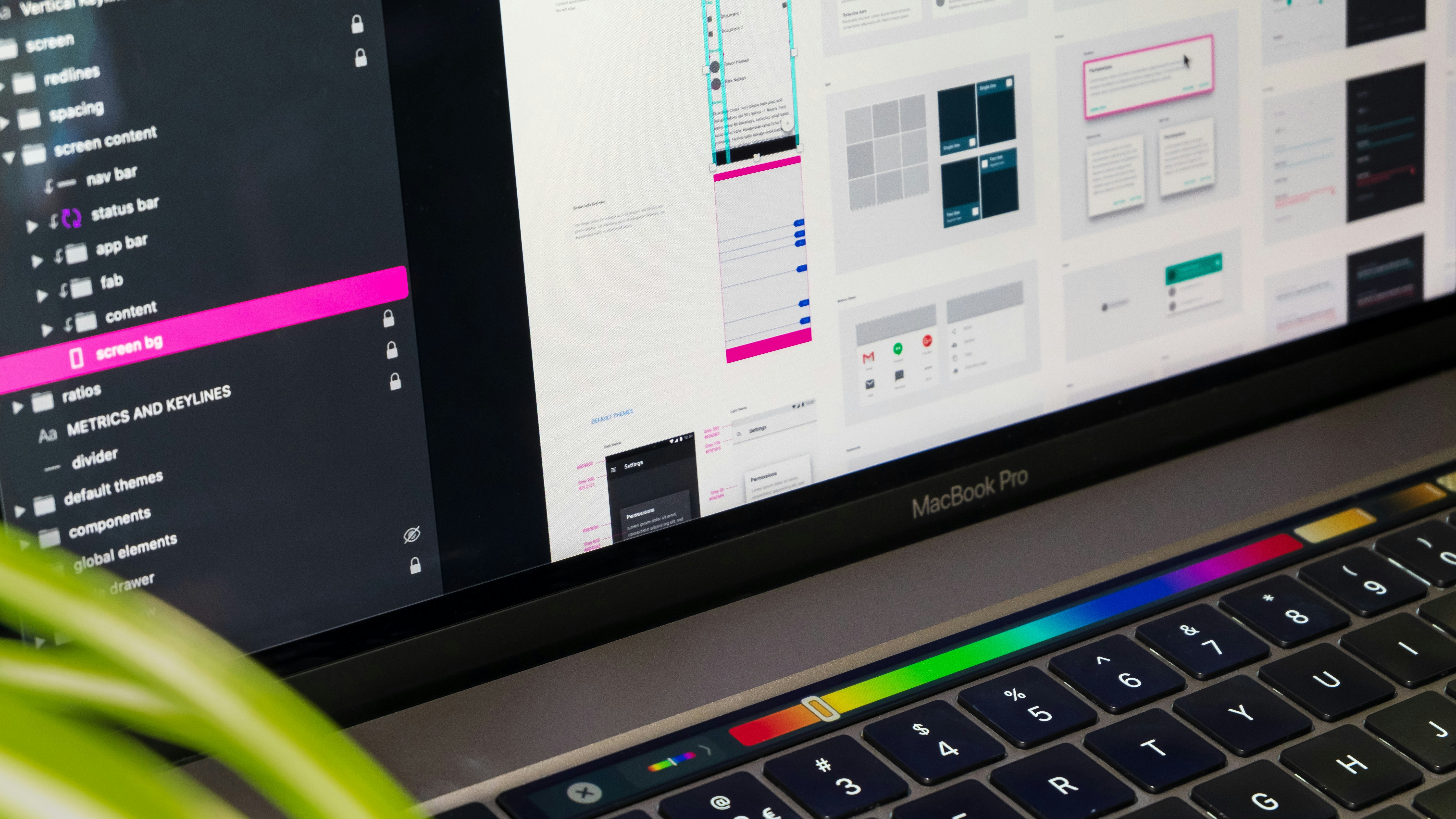 Close-up of a MacBook Pro displaying a user interface design application with folders and design previews on screen.