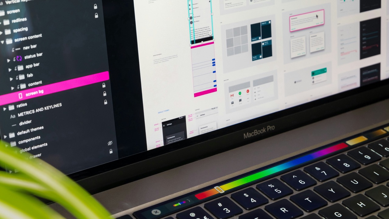 Close-up of a MacBook Pro displaying a user interface design application with folders and design previews on screen.