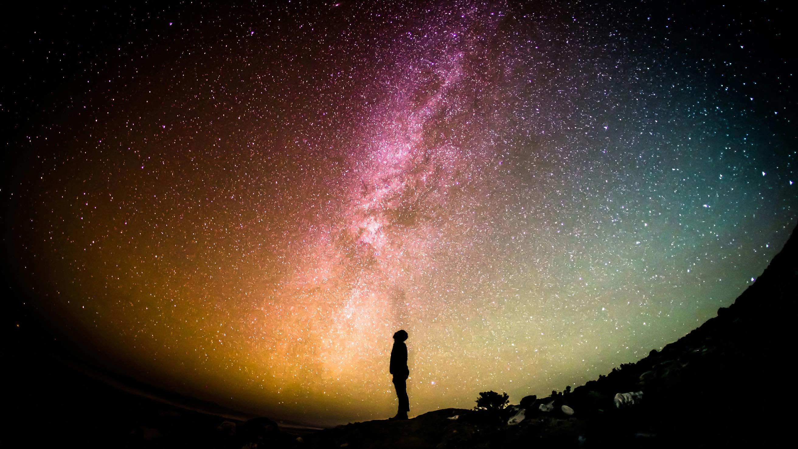 Person silhouetted against starry night sky with Milky Way