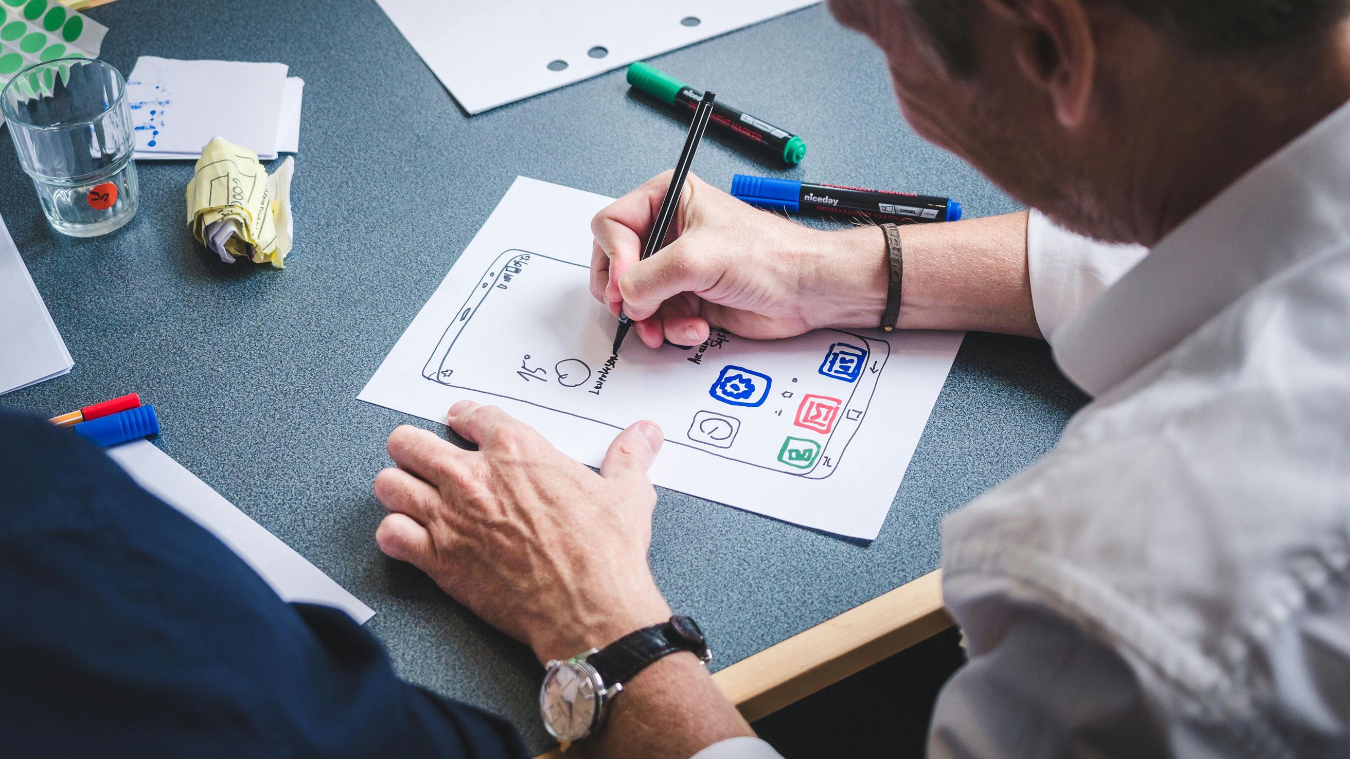 Designer sketching mobile app interface on paper