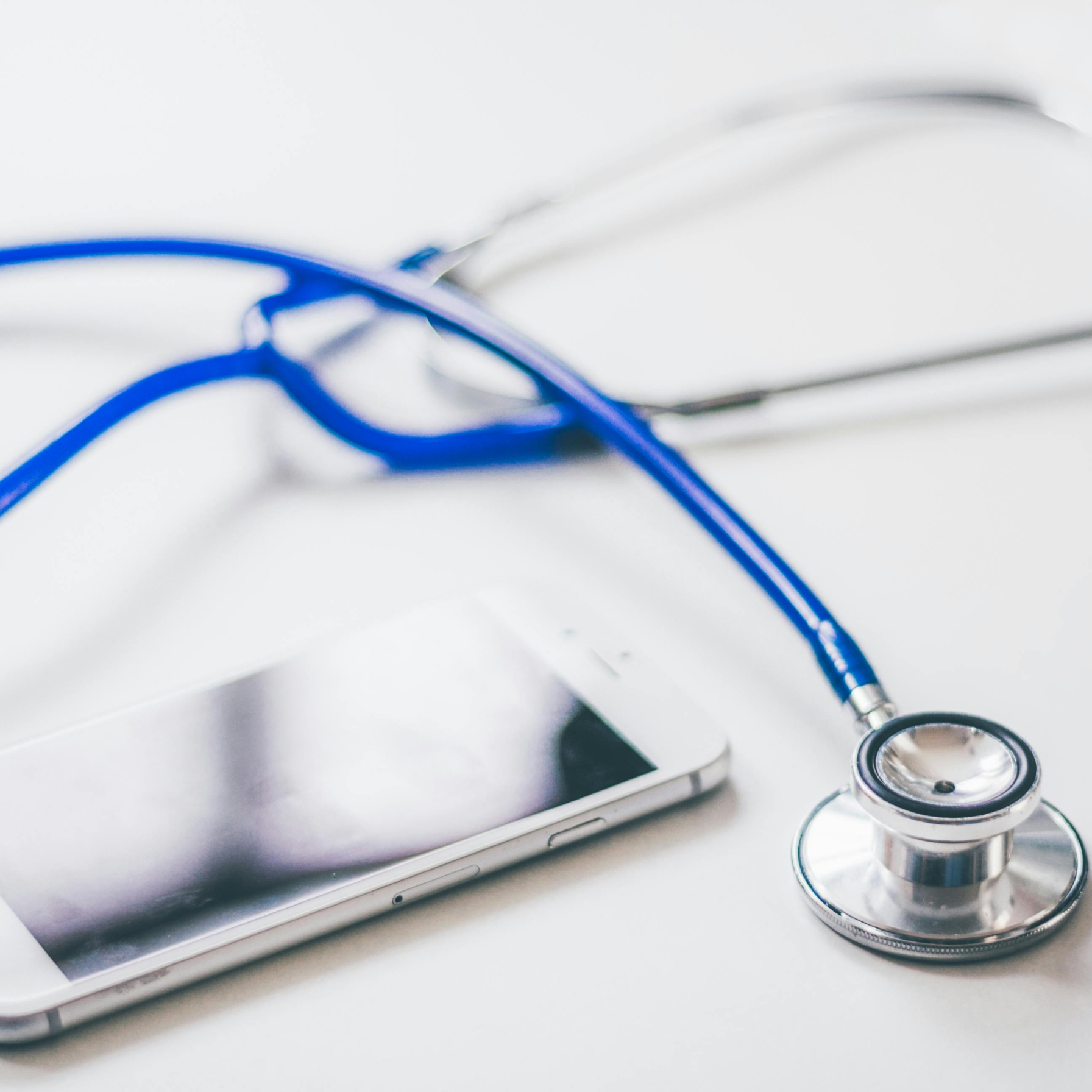 A stethoscope lying on a white surface next to other medical tools, symbolizing healthcare or medical technology.